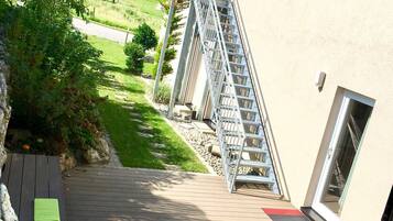 Eine Holzterrasse führt zu einem Gebäude mit einer Metalltreppe und einer Glastür.