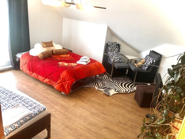 A bedroom with a bed, a desk, a chair, and a zebra-patterned rug.