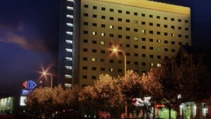 A multi-story hotel with a green sign at the top. - Benjoy Hotel Shanghai (Shanghai)