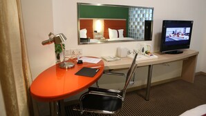 A hotel room with a desk, chair, television, and a mirror. - Benjoy Hotel Shanghai (Shanghai)
