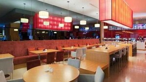 A modern restaurant with round tables and booths, red seating, and pendant lighting. - Benjoy Hotel Shanghai (Shanghai)