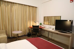 A hotel room with a bed, a desk with a chair, a television, and a window with curtains. - Benjoy Hotel Shanghai (Shanghai)