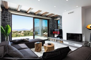 Ein modernes Wohnzimmer mit Steinwand, großem Fernseher und Blick ins Freie.