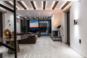 Un salon moderne avec un mur d’accent en pierre, une grande fenêtre donnant sur un paysage magnifique et une cheminée.
