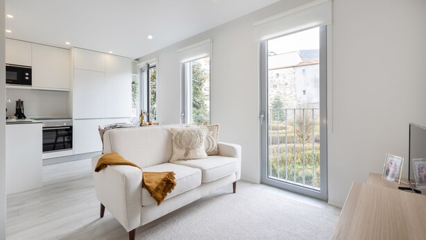 Un appartement moderne comprenant un espace de vie, une cuisine et de grandes portes-fenêtres coulissantes donnant sur un balcon.