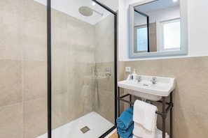 A modern bathroom with a glass-enclosed shower, a white sink, and a mirror above it. - Boutique Hostal Oriola (Pollença)