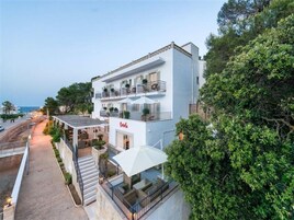 Un hotel de varios pisos con mesas al aire libre y vista al mar.