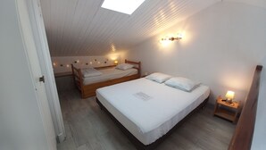 Een slaapkamer met twee bedden, een dakraam en wandlampen.