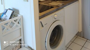 Een kleine keuken met een wasmachine, een spoelbak en een droogrek.