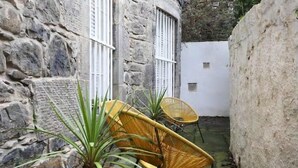 A stone building with a small courtyard, featuring two wicker chairs and potted plants. - JOIVY Vibrant City Centre 2-bed Apt. (Edinburgh)