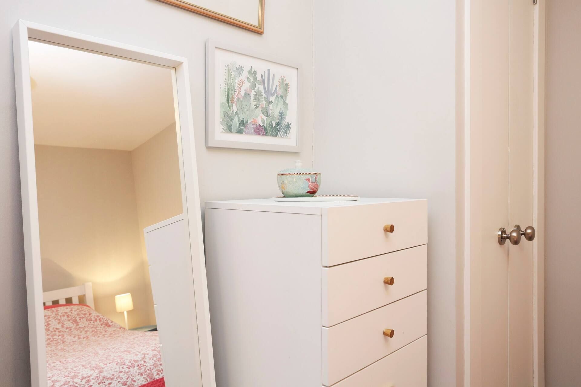 A bedroom with a bed, a dresser, a mirror, and a framed picture on the wall.