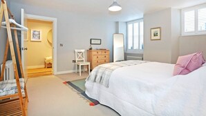 A bedroom with a bed, a dresser, a chair, a mirror, and a door leading to another room. - JOIVY Vibrant City Centre 2-bed Apt. (Edinburgh)