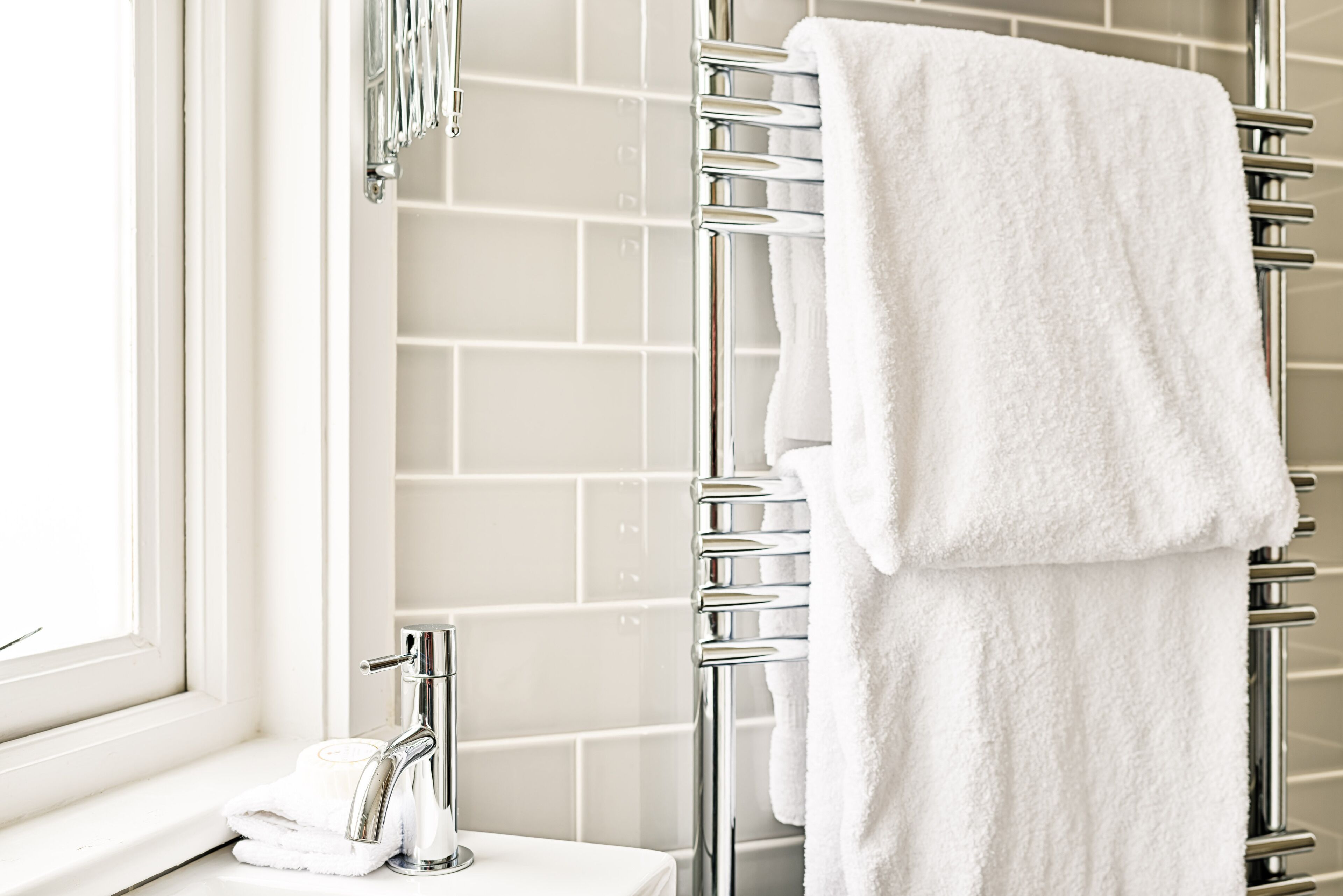 A bathroom with a white sink, chrome faucet, and a towel rack with a white towel.