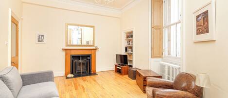 A spacious living room with a fireplace, a television, and a bookshelf.