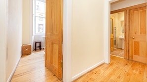Un pasillo con piso de madera y puertas que dan a un baño.