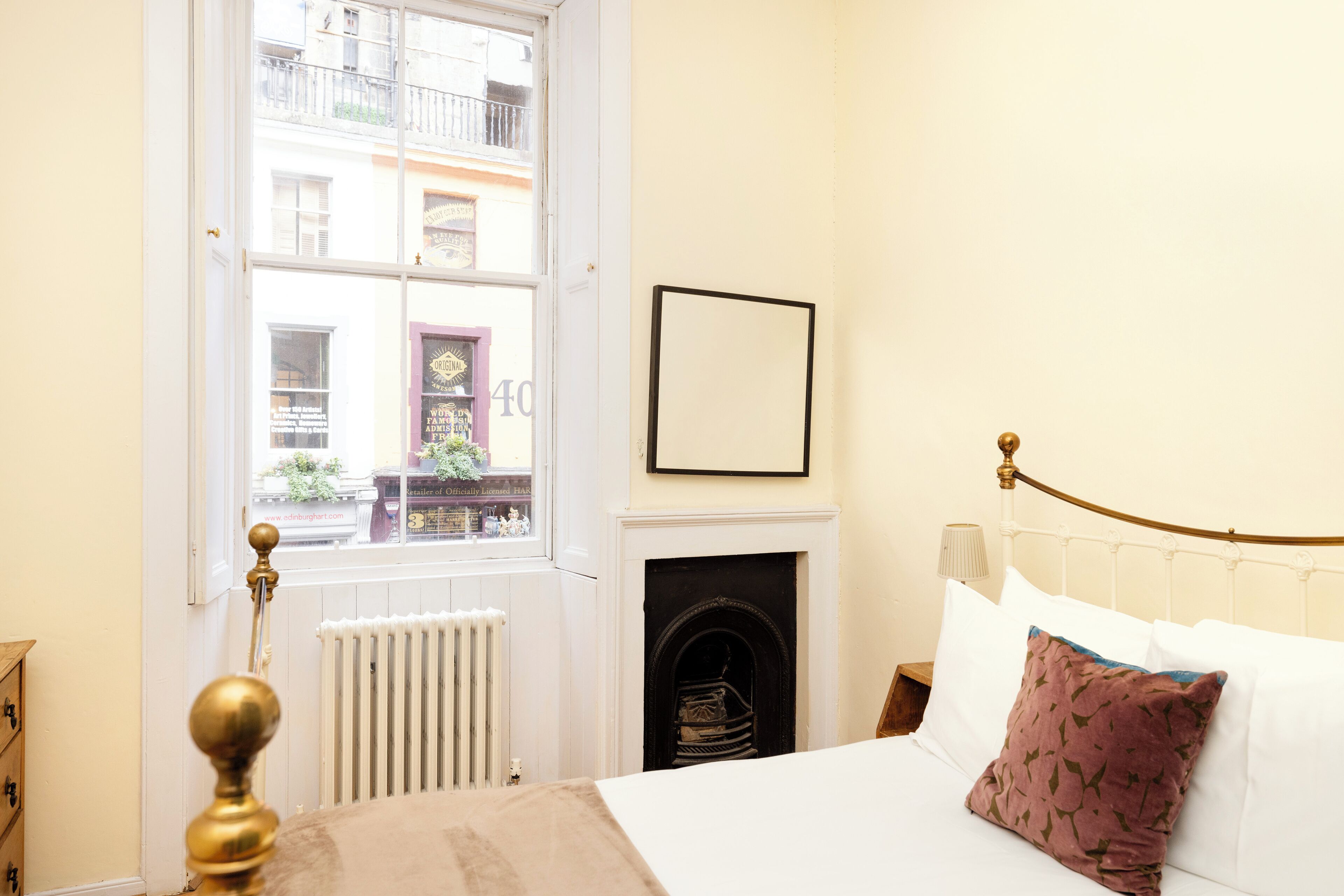 Un dormitorio con cama, chimenea, ventana y vista a la calle.