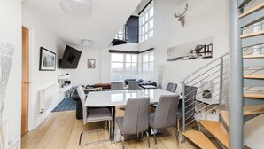 Ein moderner Essbereich mit großem Tisch, Stühlen und einer Treppe.