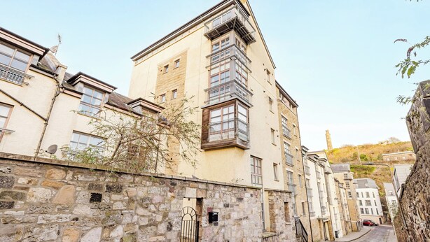 Eine enge Kopfsteinpflasterstraße, gesäumt von historischen Gebäuden aus Stein mit zahlreichen Fenstern und Balkonen.
