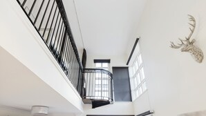 Ein Zimmer mit hohen Decken, einem Balkon, großen Fenstern und einem aufgehängten Hirschkopf.