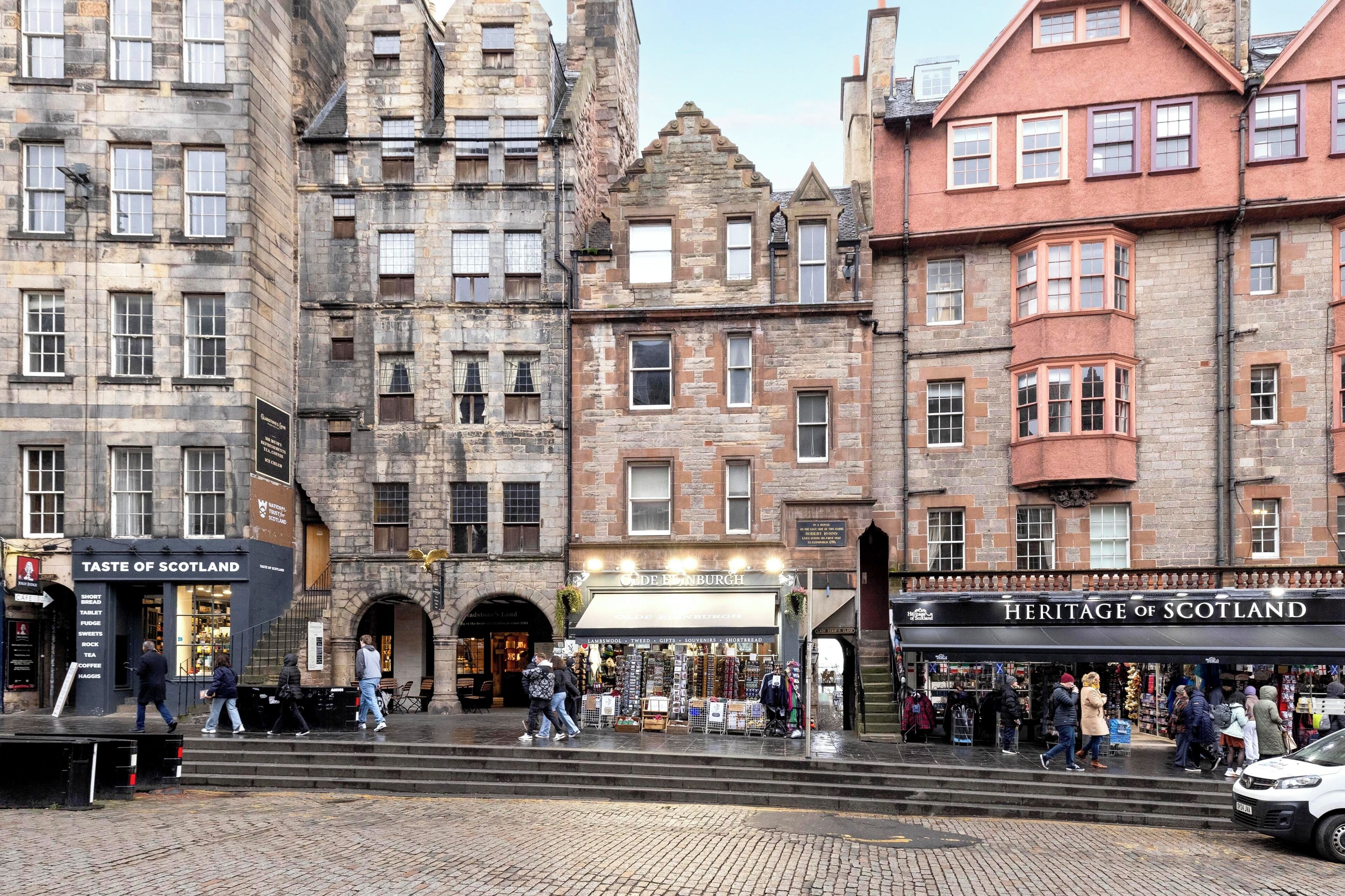 A street scene with historic buildings, a shop named "Taste of Scotland," and another named "Heritage of Scotland."