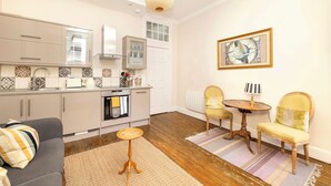 A modern kitchen with a dining area, featuring a sofa, chairs, and a small table. - JOIVY Royal Mile Tower Apartment (Edinburgh)