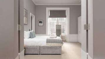 Un dormitorio con una cama grande, una ventana con persianas, un radiador y un espejo en la pared.