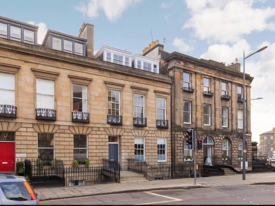 Una hilera de casas adosadas tradicionales con un estilo arquitectónico uniforme, con ventanas y balcones simétricos.