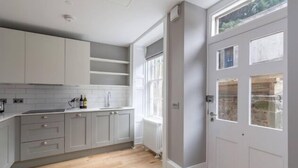 A kitchen with grey cabinets, a white countertop, and a wooden floor. - JOIVY Luxury Georgian City Centre Apartment (Sleeps 6) (Edinburgh)