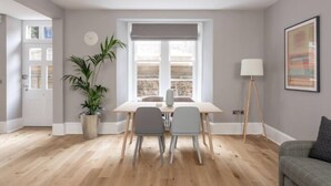 A modern dining area with a wooden table and two chairs, a potted plant, and a lamp. - JOIVY Luxury Georgian City Centre Apartment (Sleeps 6) (Edinburgh)