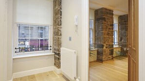 Habitación con ventana, pared de piedra, radiador y suelo de madera.