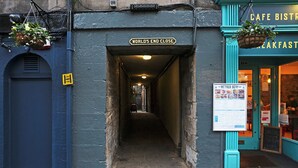 A narrow alleyway with a sign reading "WORLD'S END CLOSE" and a cafe entrance with a menu board. - JOIVY Newly Refurbished Apartment on the Historic Royal Mile (Edinburgh)