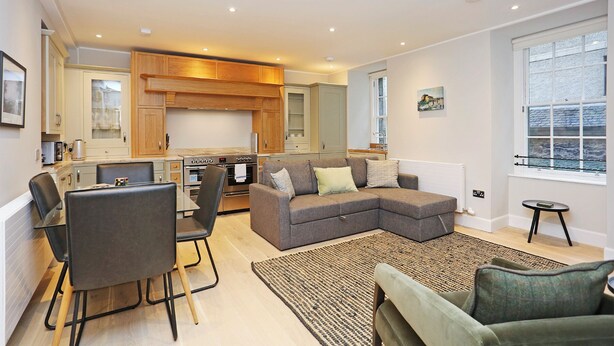 A modern living space with a dining area, kitchen, and seating area. - JOIVY Newly Refurbished Apartment on the Historic Royal Mile (Edinburgh)