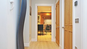 A hallway leading to a kitchen with wooden cabinets and a dining area. - JOIVY Newly Refurbished Apartment on the Historic Royal Mile (Edinburgh)