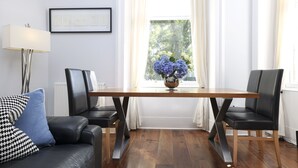 A modern living room with a wooden dining table, black leather chairs, a black and white patterned sofa, and a vase of flowers on the table. - JOIVY Stunning Ground-floor 2bedrm New Town Apt (Edinburgh)