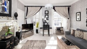 Una sala de estar moderna con un televisor de pantalla plana, sofá y plantas decorativas.