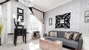 Una sala moderna con un sofá gris, una mesa de centro de madera y una mesita auxiliar negra con lámparas.