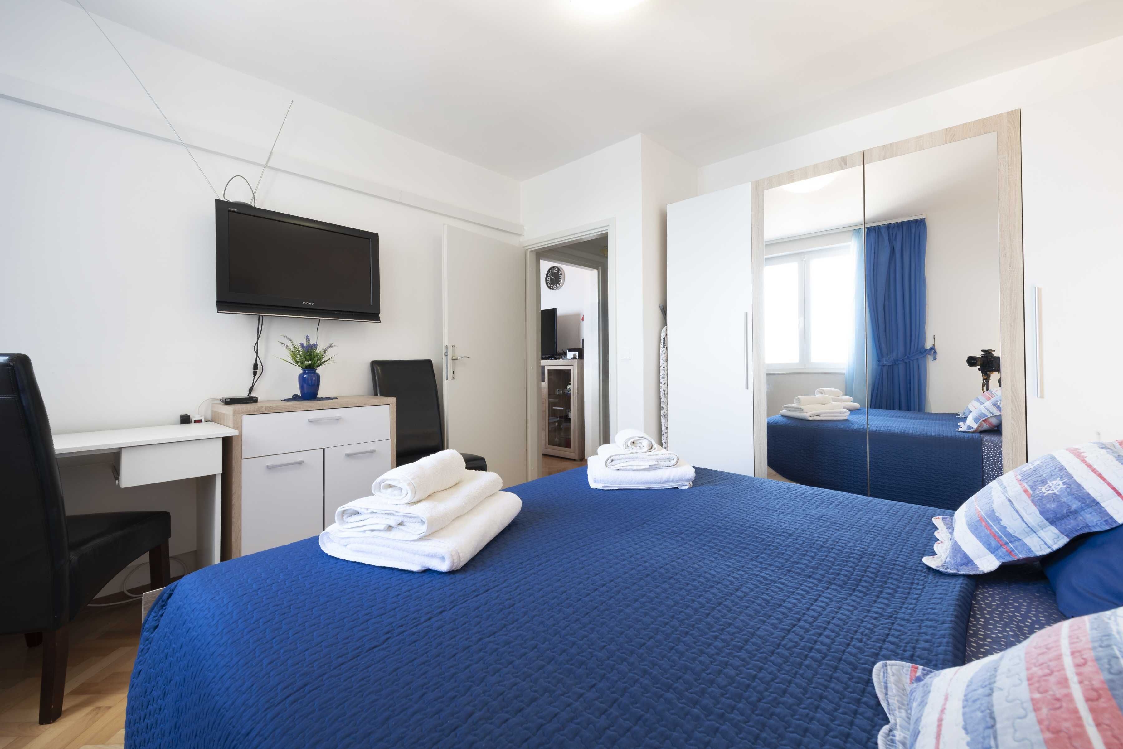 Une chambre d’hôtel comprenant un lit, un bureau avec une chaise, un téléviseur fixé au mur et une armoire.