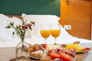 Desayuno con cruasanes, fresas, queso y jugo de naranja sobre una mesa de madera.