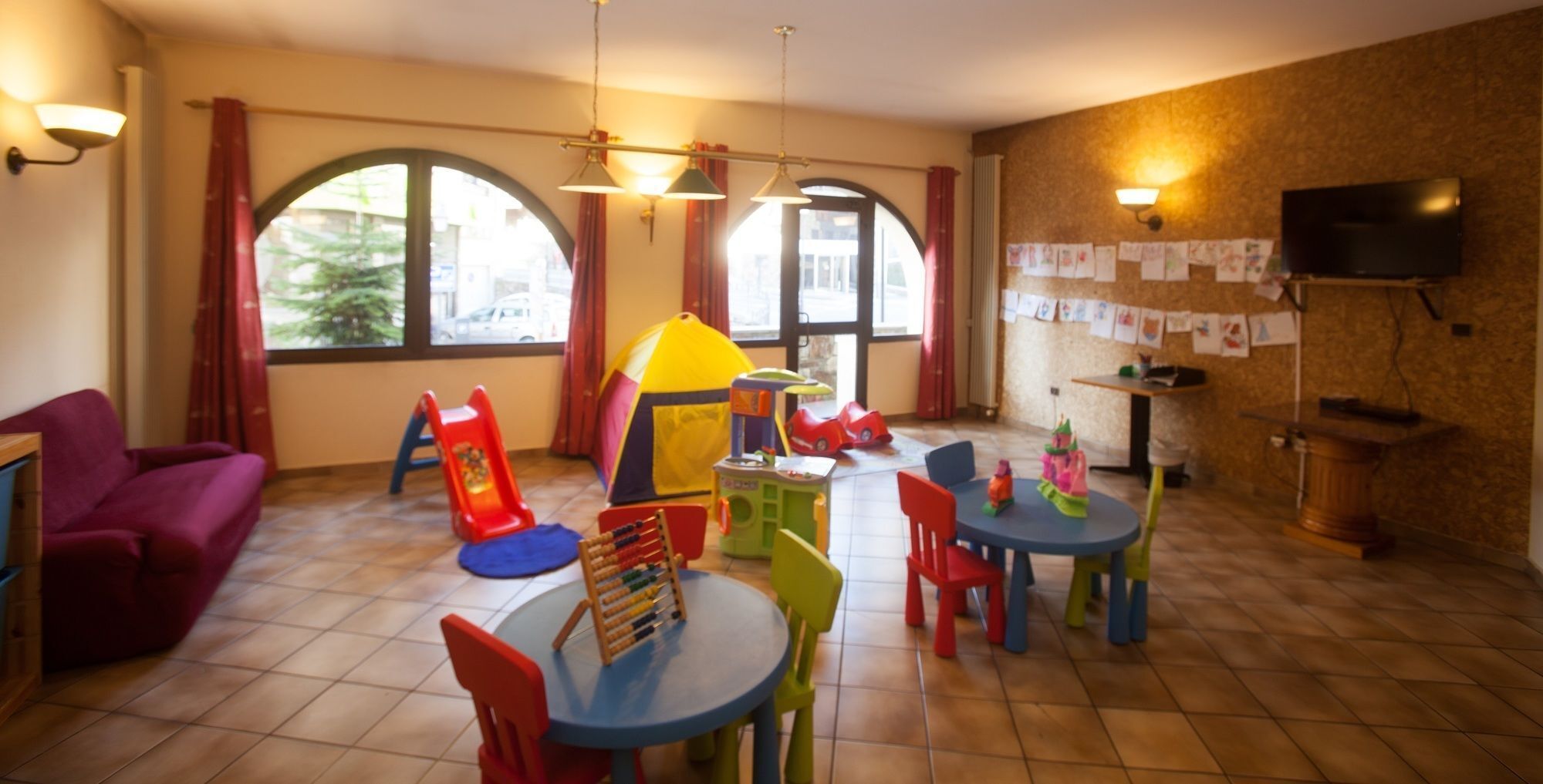 Un área de juegos infantiles con un tobogán, tiendas de campaña y sillas coloridas.