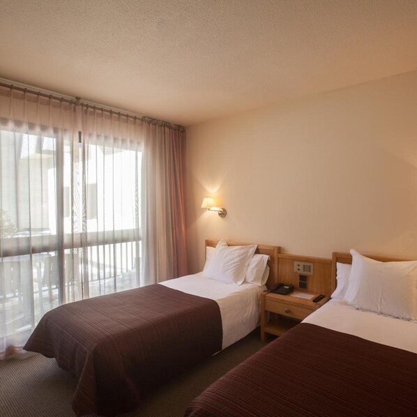 A hotel room with two beds, a nightstand, a lamp, and a window with curtains. - Bonavida (Canillo)