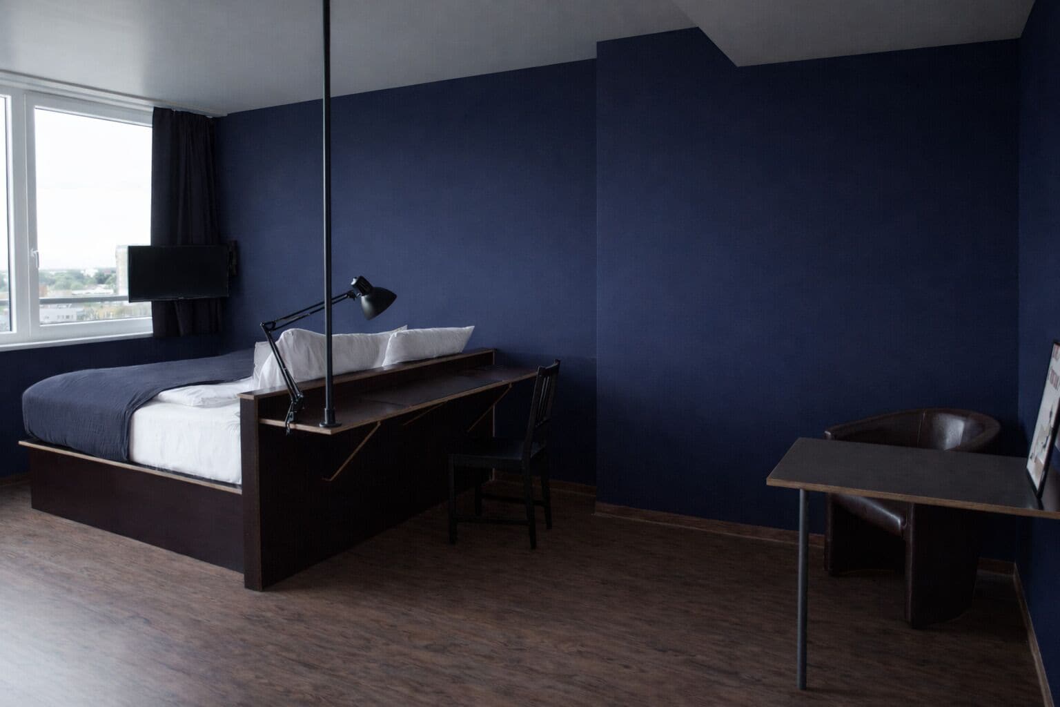 Un dormitorio con cama, escritorio, silla y ventana.