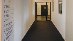 Un couloir avec un panneau indicateur sur le côté gauche, qui mène à une porte au bout.