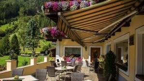 An outdoor patio with wicker furniture, a covered seating area, and flower boxes on the balcony. - Hotel Jagerhof (Kaunertal)