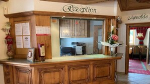 A reception desk with a wooden finish, a glass partition, and a sign that reads "Rezeption". - Hotel Jagerhof (Kaunertal)