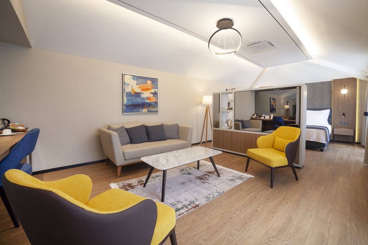 A modern living room with a sofa, two armchairs, a coffee table, and a painting on the wall.