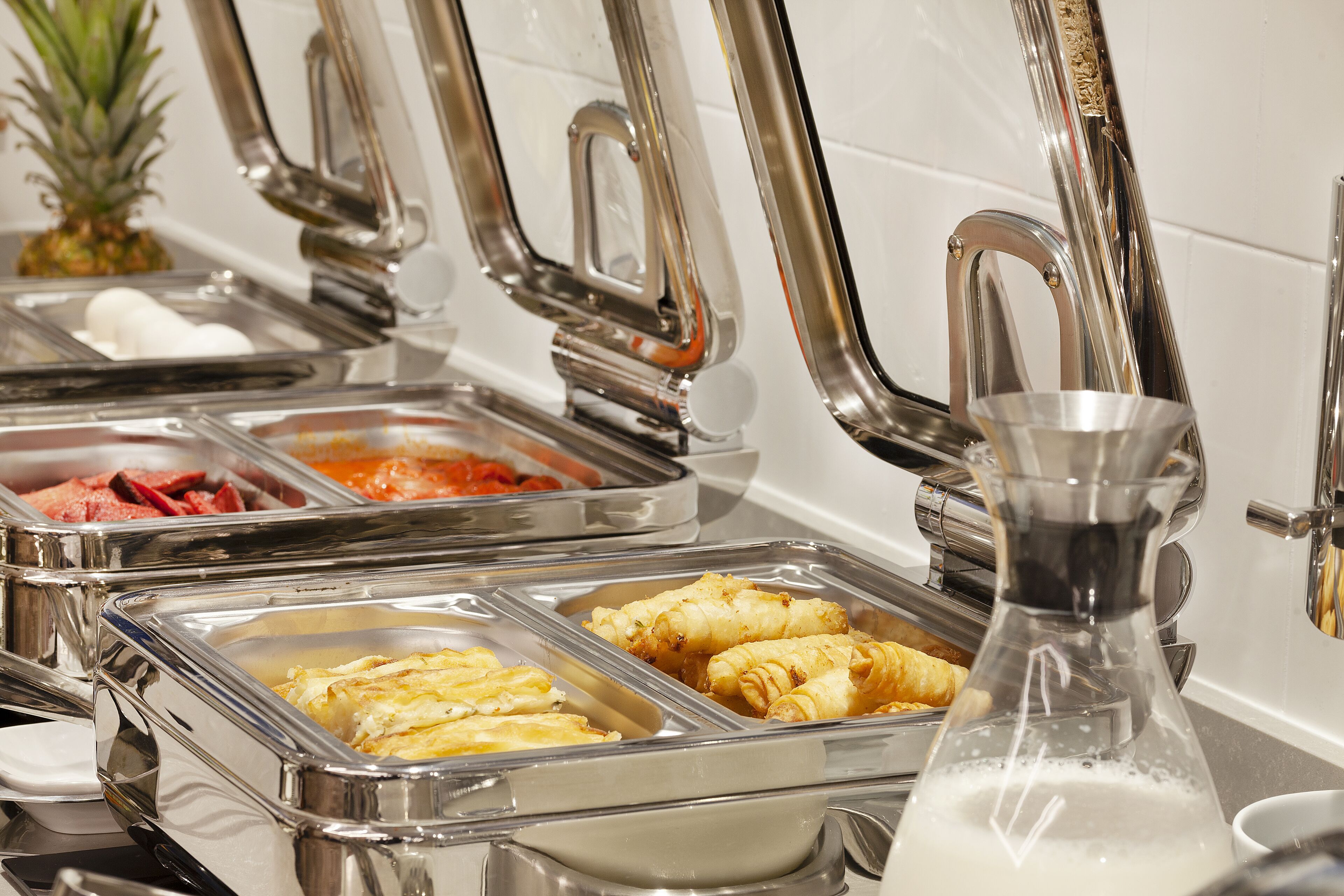 A buffet with various food items and a milk dispenser.