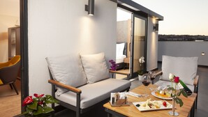 A modern outdoor seating area with a sofa and chairs, a dining table with plates and glasses, and a rose on the table. - Granbella Hotel (Tekirdag)