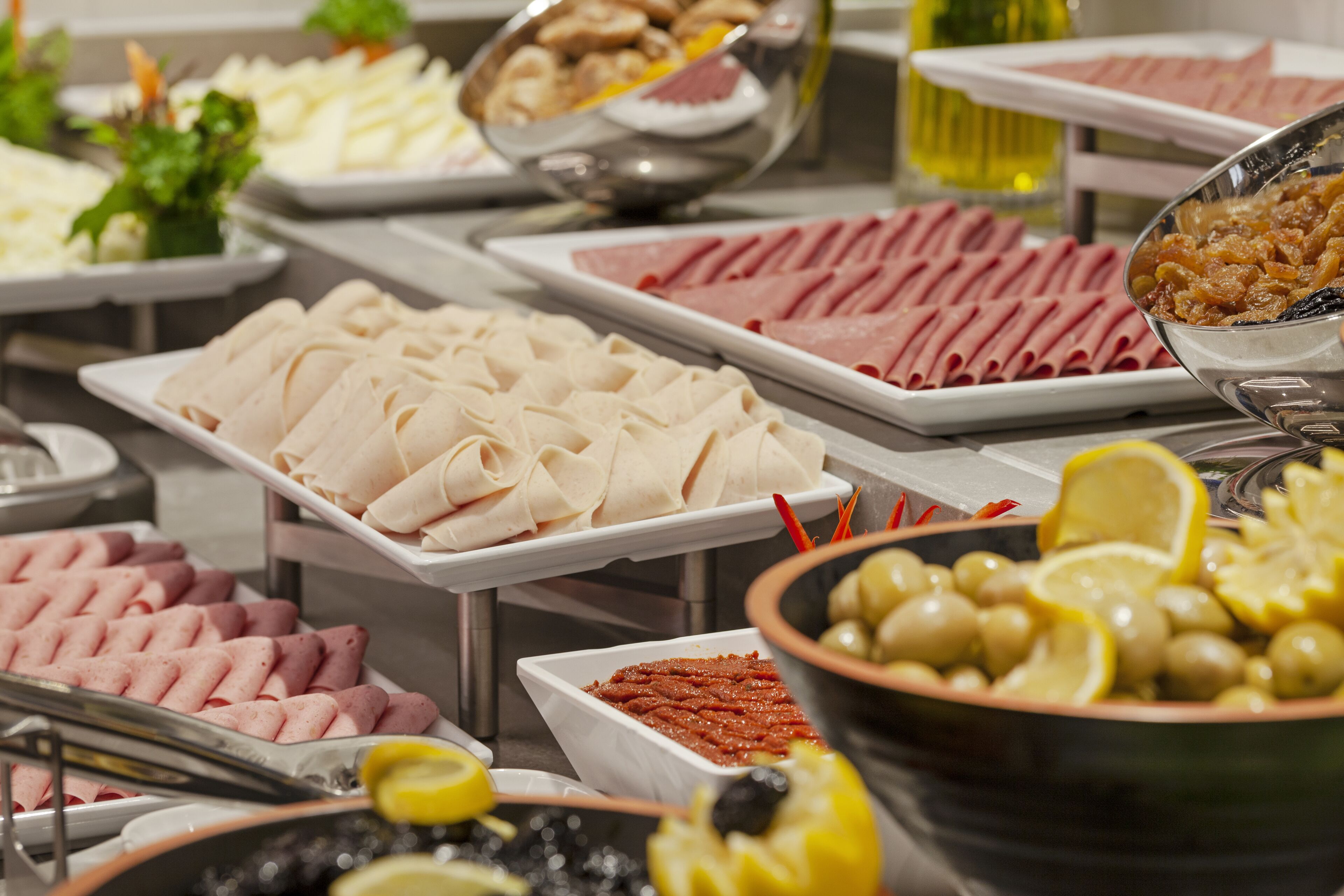 A buffet with various food items including meats, cheeses, and olives.