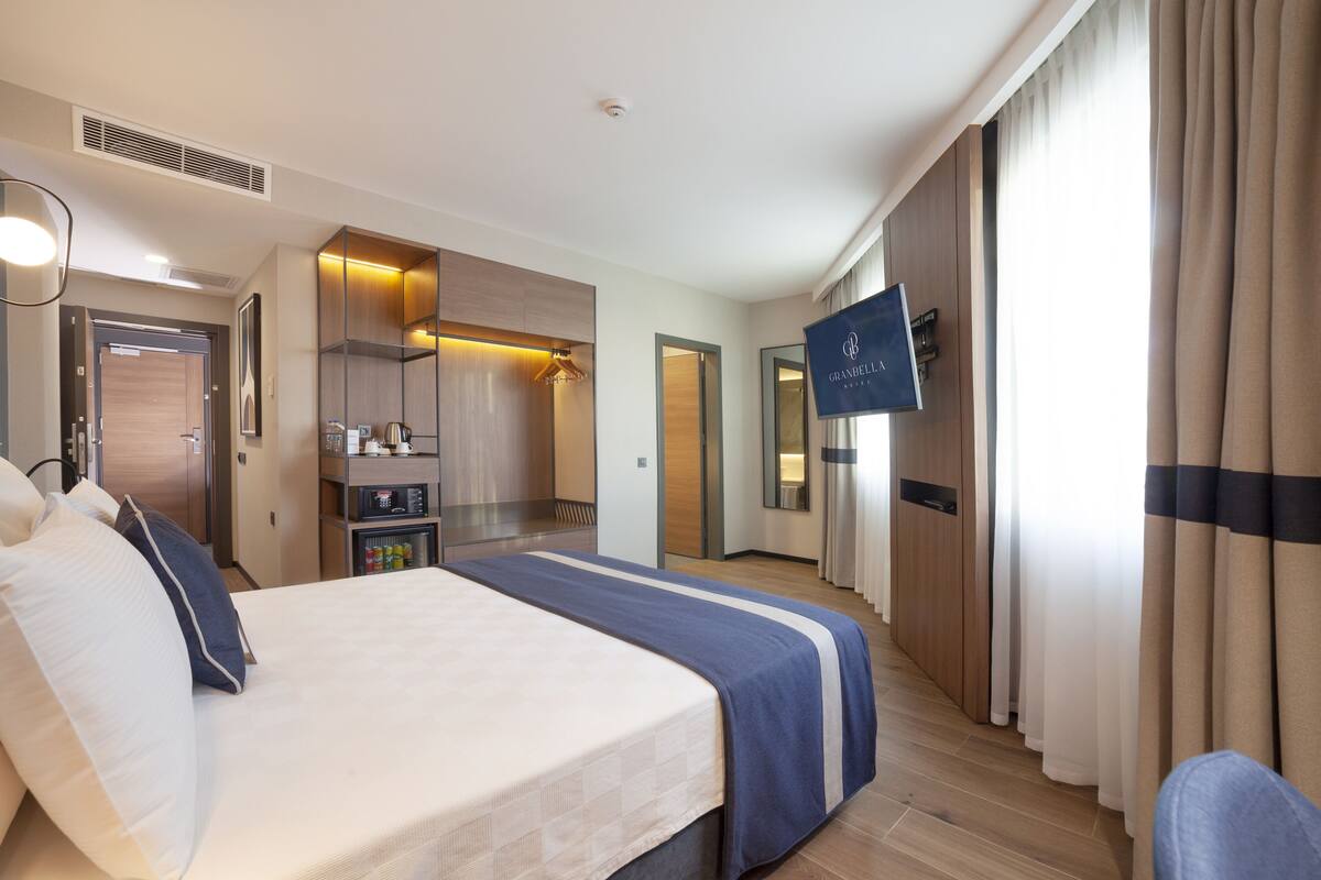 A hotel room with a bed, a TV, a wardrobe, a mirror, and a bathroom.