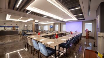 A conference room with a long table, chairs, a podium, and a presentation screen.